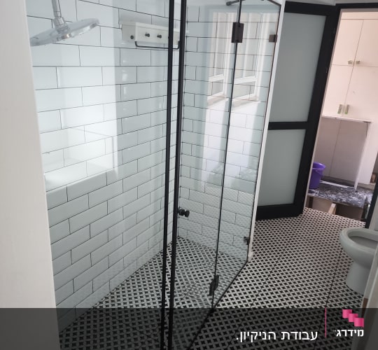 מקלחת נקייה עם אריחים לבנים ודלת זכוכית